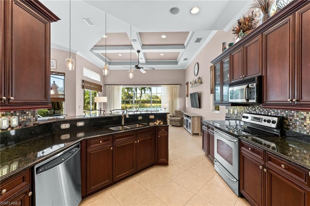7875 Valencia Court Naples, FL 34113 - Photo 7 of 38 Kitchen featuring backsplash, stainless steel appliances, coffered ceiling, granite counters, and pendant lighting