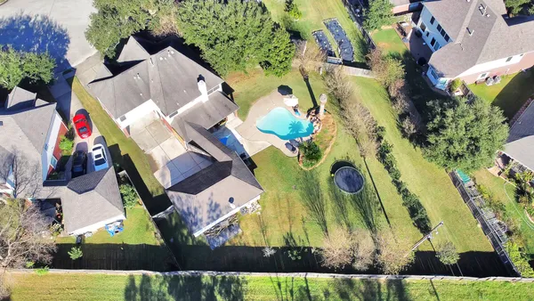 an aerial view of a house with swimming pool and large trees