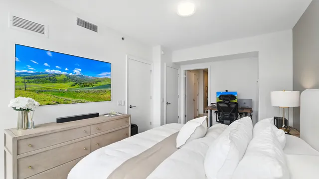 a bedroom with a bed and a flat tv screen on dresser