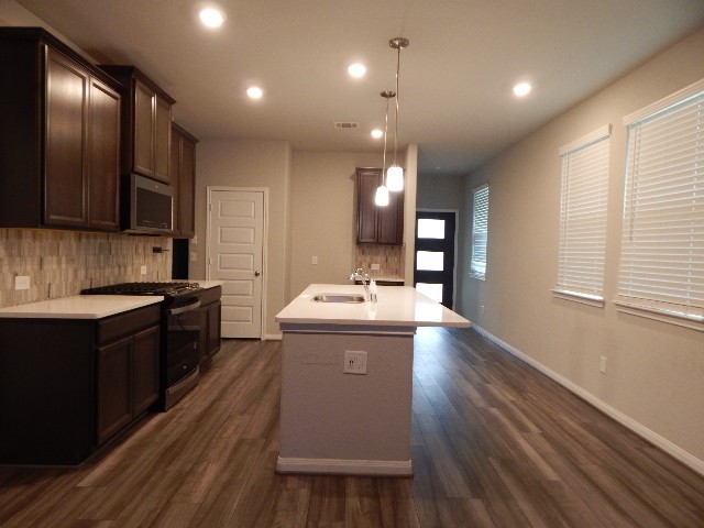 7103 Silverleaf Oak Street Conroe, TX 77304 - Photo 7 of 20 a large kitchen with kitchen island a sink dishwasher a stove and a refrigerator with wooden floor