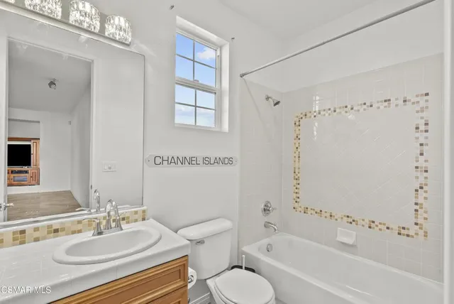 a bathroom with a double vanity sink a toilet a mirror and bathtub