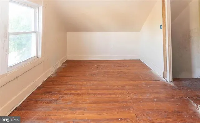 a view of a bedroom with wooden floor and a window