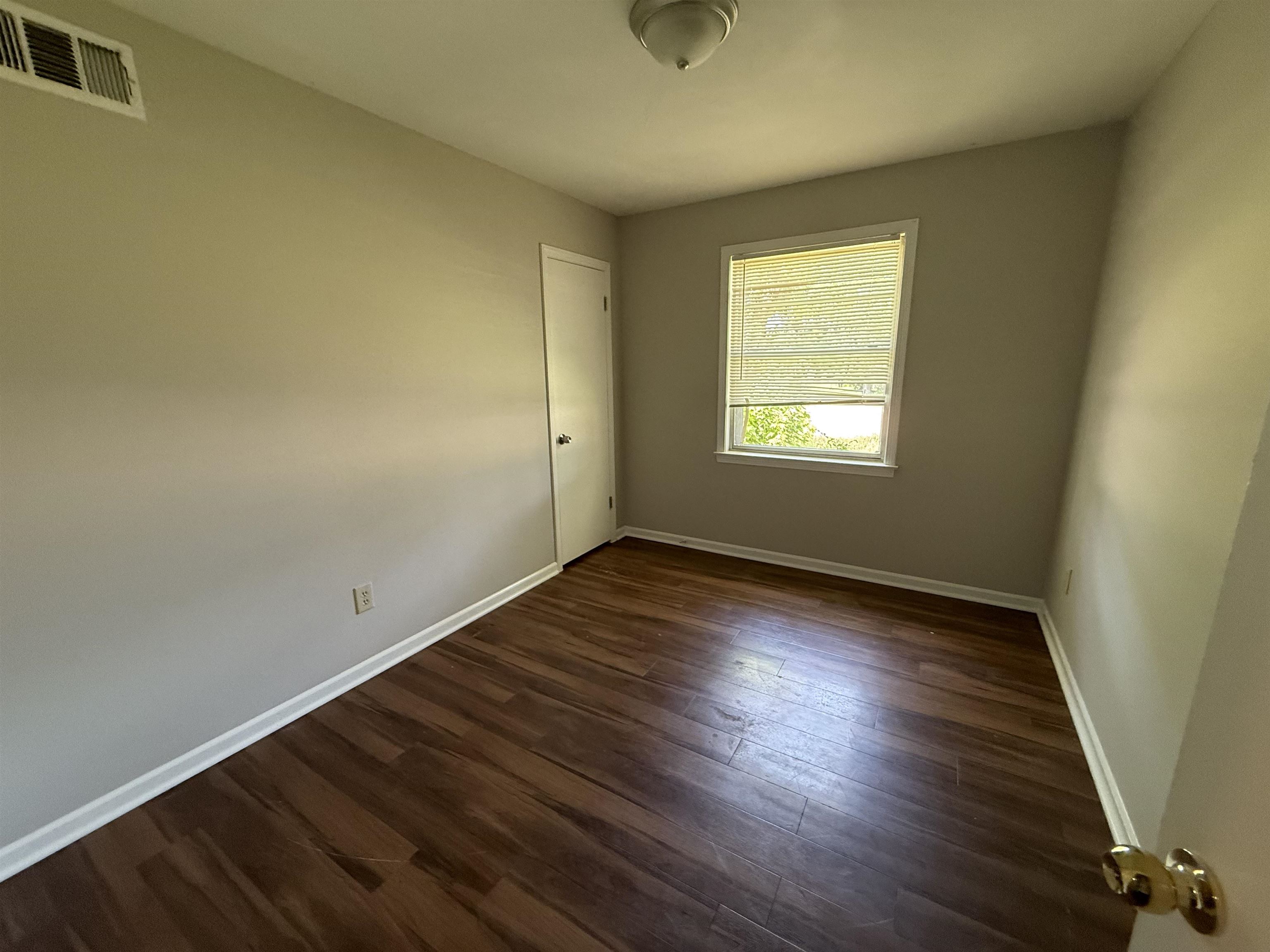 4592 Neely Road Memphis, TN 38109 - Photo 5 of 8 a view of an empty room with wooden floor and a window