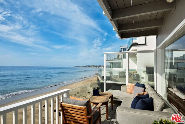 a view of a balcony with chairs and wooden fence