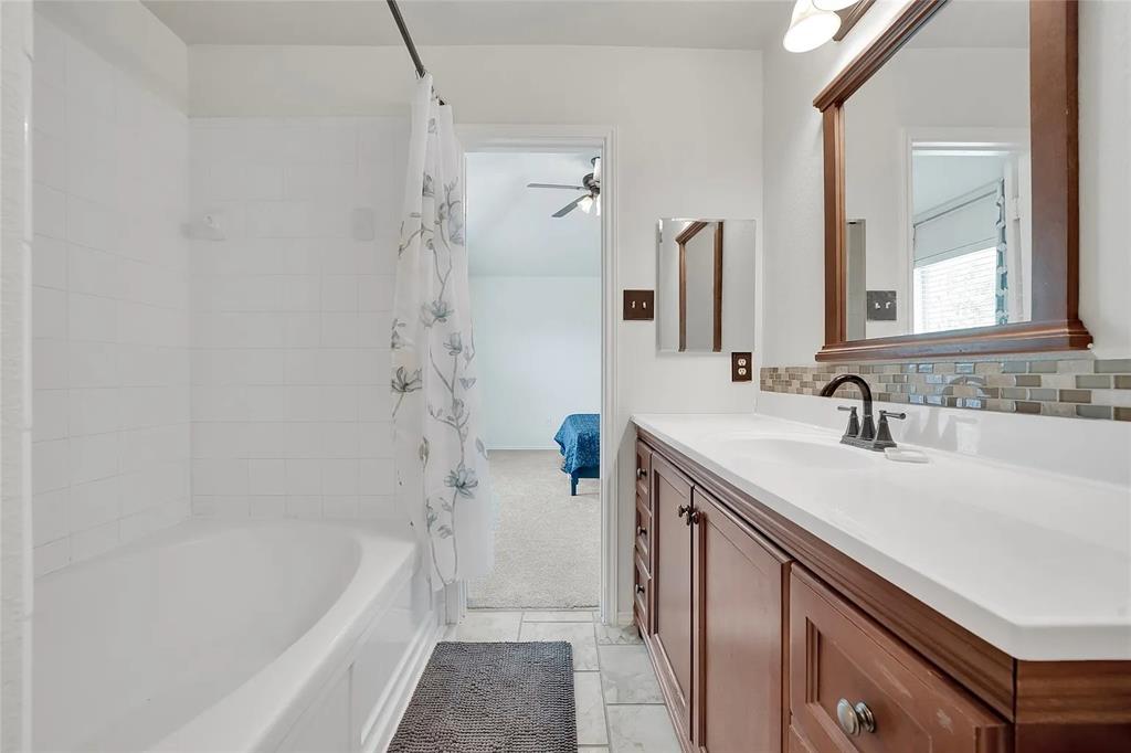 713 Baldwin Road Wylie, TX 75098 - Photo 14 of 29 a bathroom with a granite countertop sink a mirror a bathtub and shower