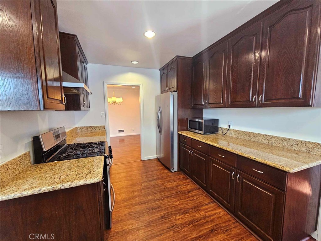 5259 Angeles Vista Boulevard View Park, CA 90043 - Photo 19 of 42 a kitchen with granite countertop wooden cabinets and stainless steel appliances