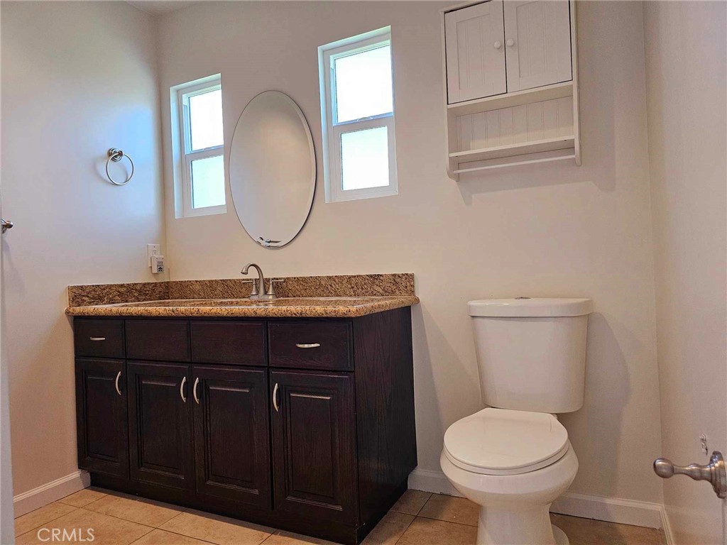 5259 Angeles Vista Boulevard View Park, CA 90043 - Photo 30 of 42 a bathroom with a granite countertop toilet sink and mirror