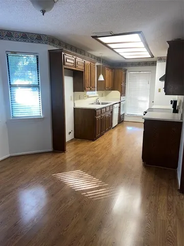 a large kitchen with stainless steel appliances granite countertop a sink stove and wooden floor