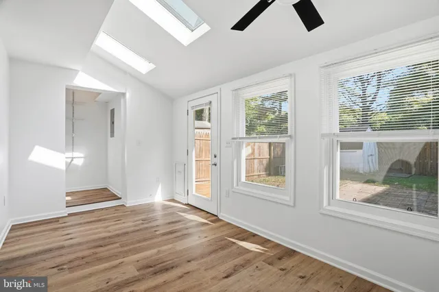 a view of an empty room with window and wooden floor