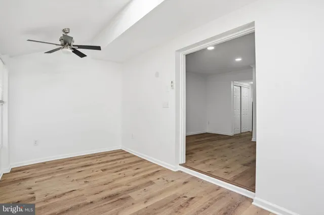 an empty room with wooden floor fan and windows