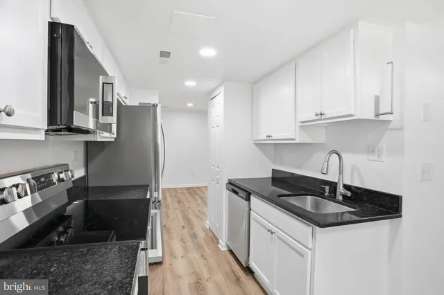 a kitchen with granite countertop a sink stove and cabinets