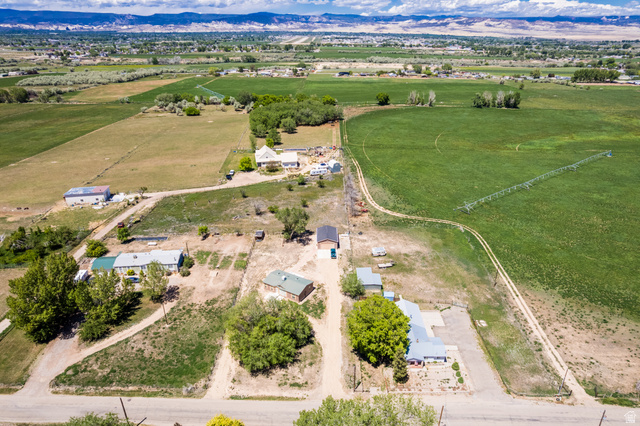 1043 East 4000th Street South Vernal, UT 84078 - Photo 27 of 31 Expansive land parcel featuring multiple residential structures, agricultural fields, and a distant mountain range