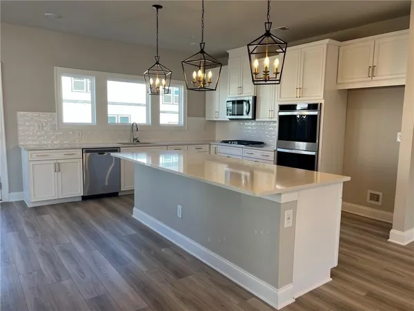 a large kitchen with granite countertop a stove top oven a sink a counter space and wooden floor