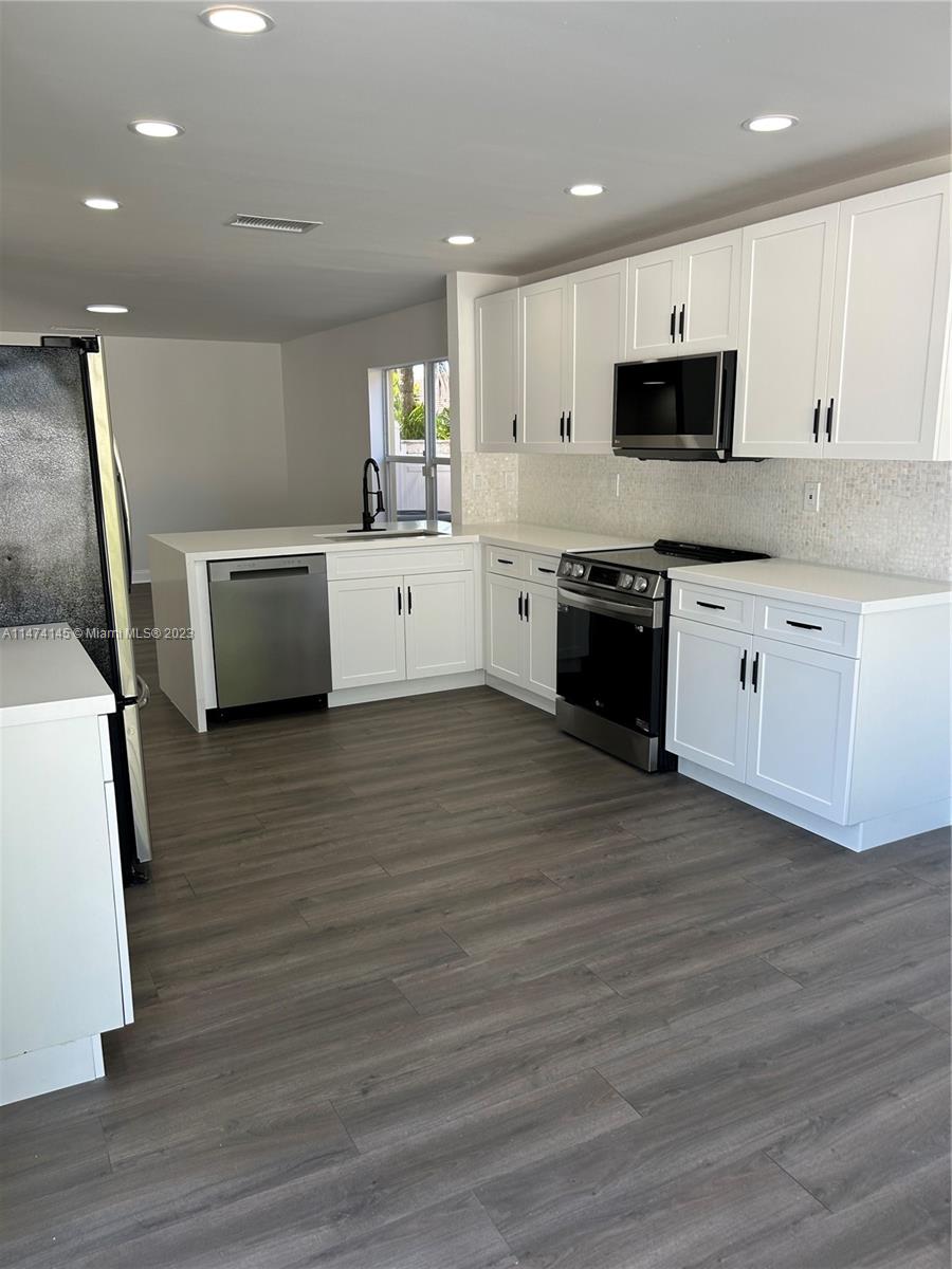Three Lakes Miami, FL 33186 - Photo 9 of 32 a large kitchen with stainless steel appliances wooden floors and wooden cabinets