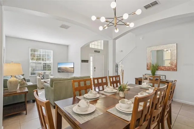 a dining room with wooden floor a chandelier fan a wooden table and chairs
