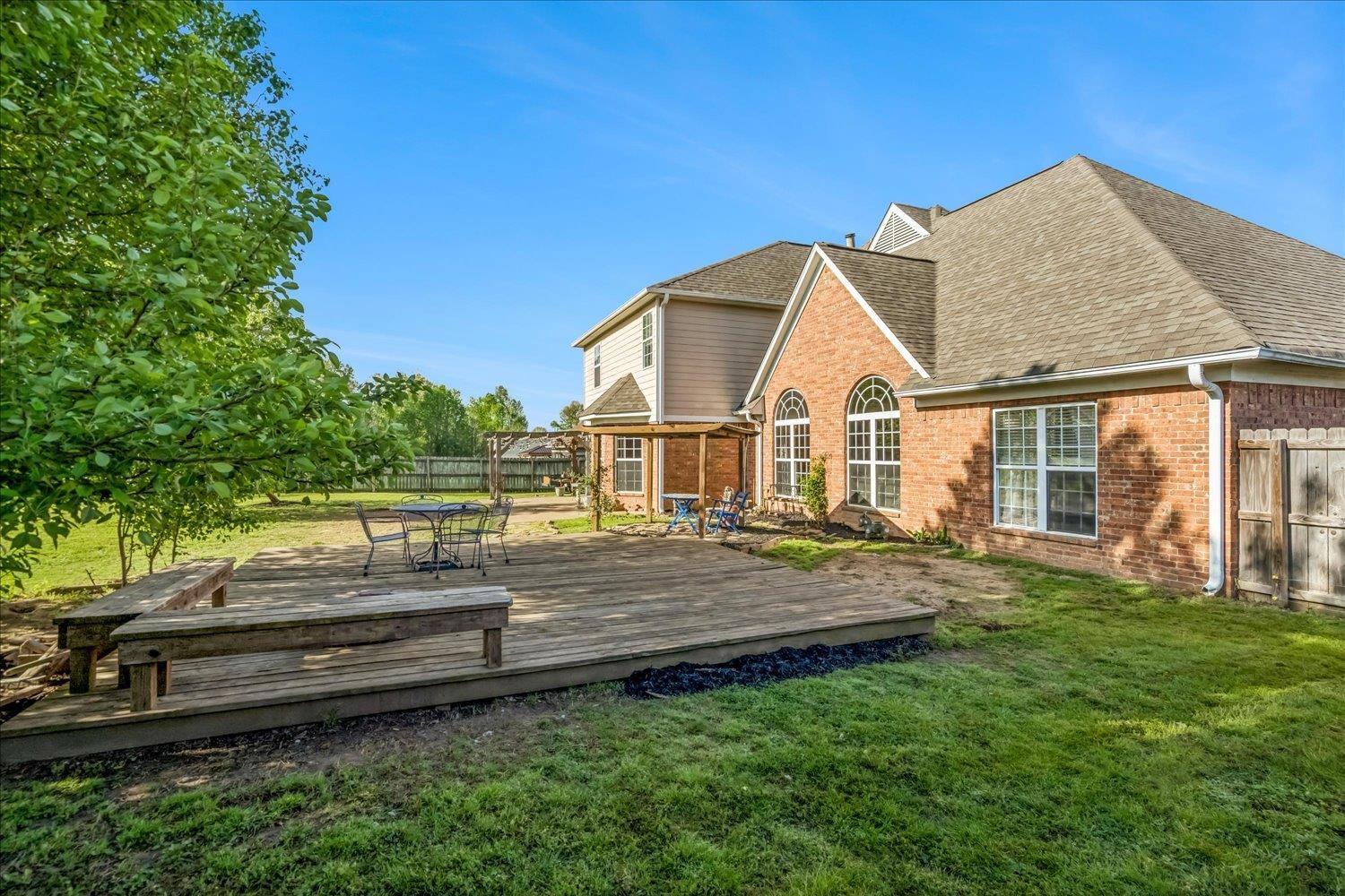 134 Rembert Drive Atoka, TN 38004 - Photo 36 of 38 Expansive wood deck with integrated benches, bordered by a manicured lawn