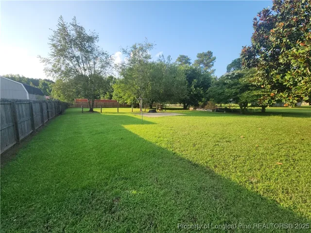 a view of a green yard with a house and large trees