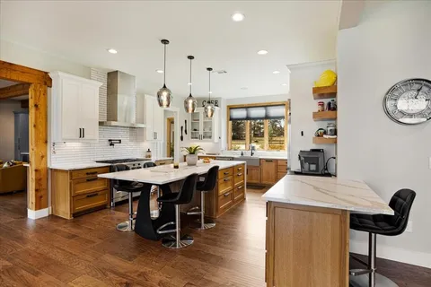 a large kitchen with stainless steel appliances kitchen island granite countertop a large stove a sink dishwasher and white cabinets with wooden floor