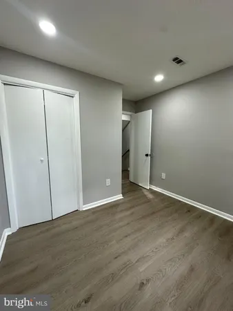 an empty room with wooden floor and closet area