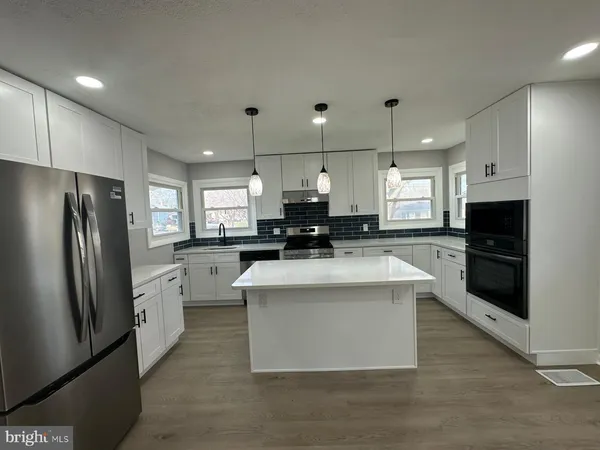 a kitchen with kitchen island white cabinets and stainless steel appliances