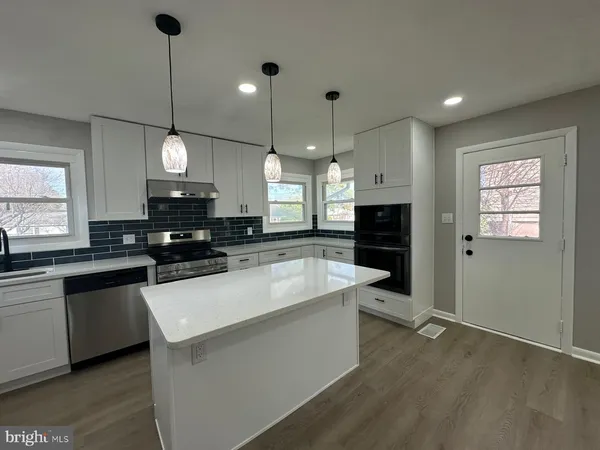 a large kitchen with stainless steel appliances a large center island attached withe living room