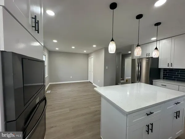 a large kitchen with stainless steel appliances a large counter top space refrigerator and a sink