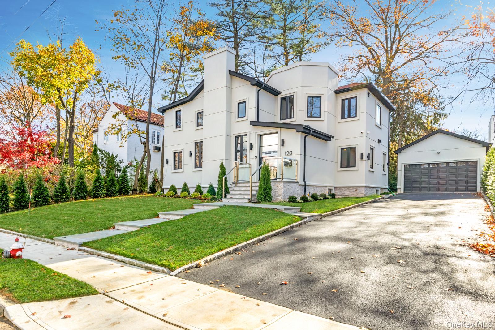 120 Baker Hill Road Great Neck, NY 11023 - Photo 2 of 25 a front view of a house with a yard and garage