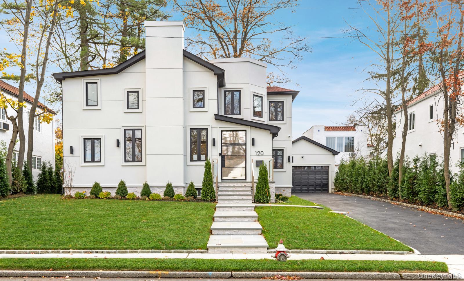 120 Baker Hill Road Great Neck, NY 11023 - Photo 3 of 25 a front view of a house with a garden and plants