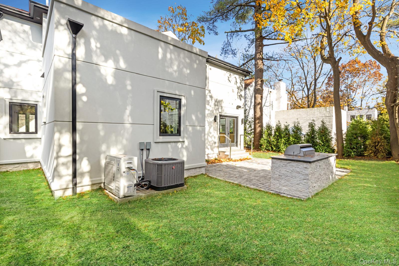 120 Baker Hill Road Great Neck, NY 11023 - Photo 5 of 25 a view of a backyard with table and chairs potted plants and large tree