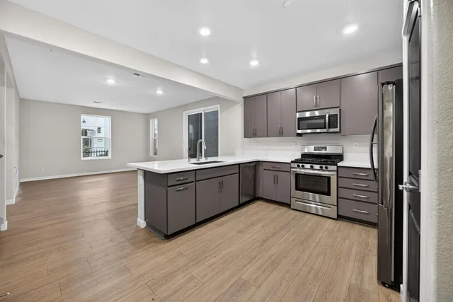 a kitchen with stainless steel appliances kitchen island granite countertop a stove a sink and a refrigerator