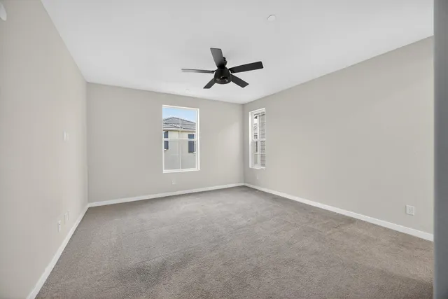 an empty room with windows and ceiling fan view