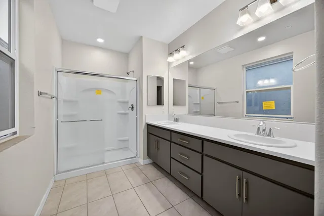 a bathroom with a double vanity sink mirror and shower