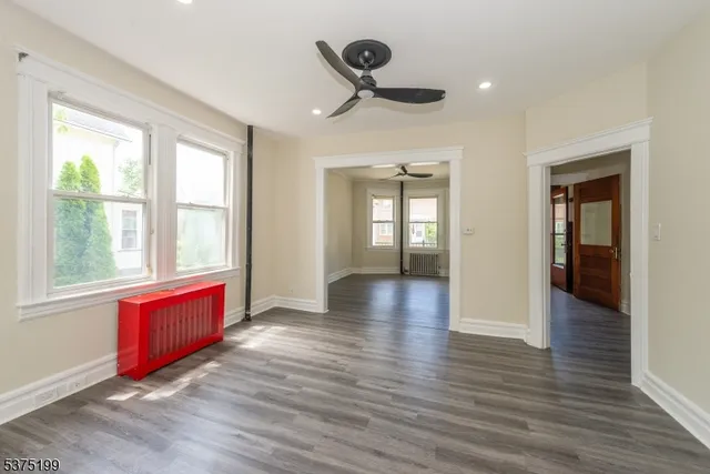 a view of an empty room with window wooden floor and a kitchen