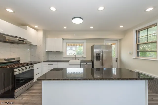 a kitchen with stainless steel appliances granite countertop a sink a stove and oven
