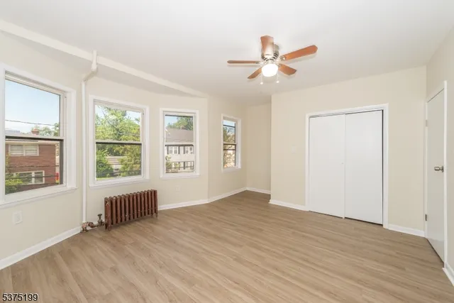 a view of an empty room with a window and wooden floor