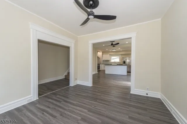 a view of a hallway with wooden floor and a kitchen space
