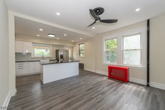 a large kitchen with stainless steel appliances granite countertop a stove a sink a refrigerator white cabinets and wooden floor