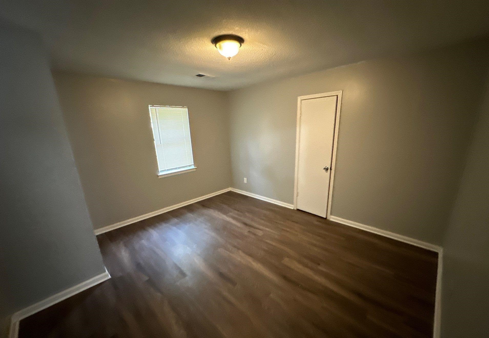 4758 11th Road Memphis, TN 38109 - Photo 5 of 8 an empty room with wooden floor and windows