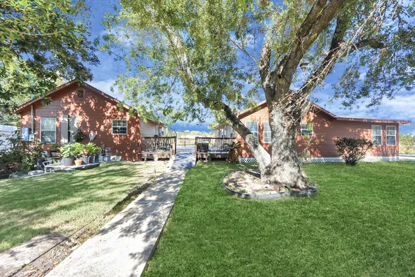 a front view of a house with a yard garden and trees