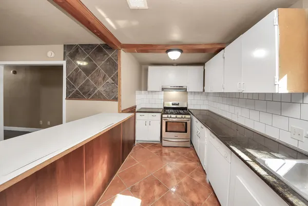 a kitchen with granite countertop white cabinets and white appliances