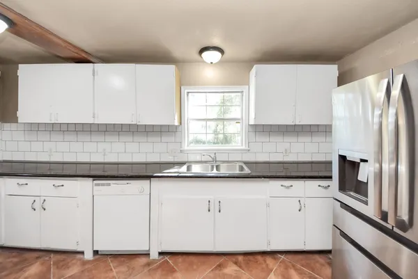 a kitchen with granite countertop white cabinets white appliances and sink