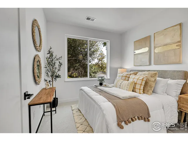 a bedroom with a bed and a chair with the large windows
