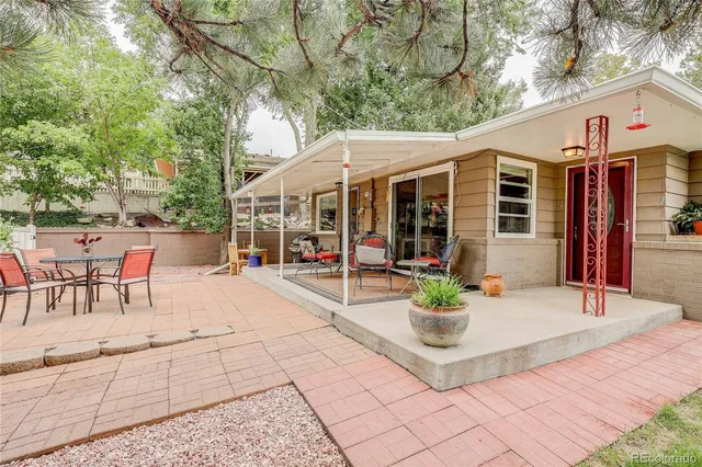 a view of a patio with table and chairs potted plants and a large tree