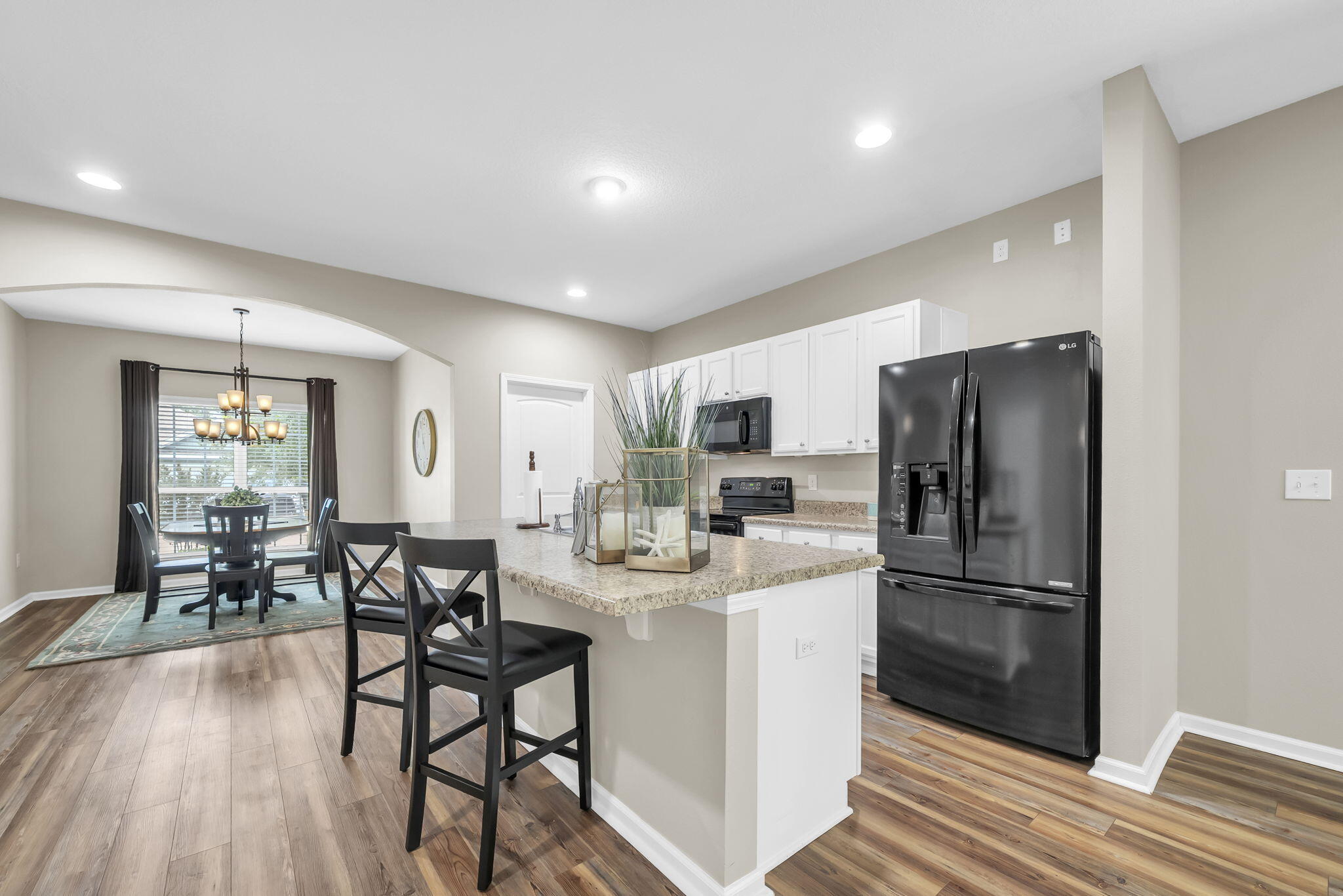 115 Lilly Bell Lane Freeport, FL 32439 - Photo 15 of 47 a kitchen with stainless steel appliances a refrigerator a stove a dining table and chairs with wooden floor