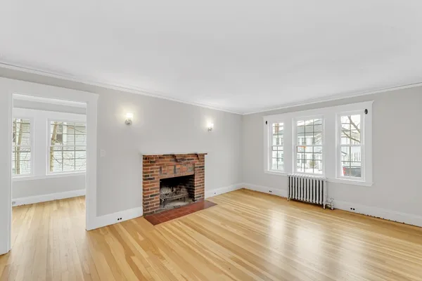an empty room with windows and fireplace