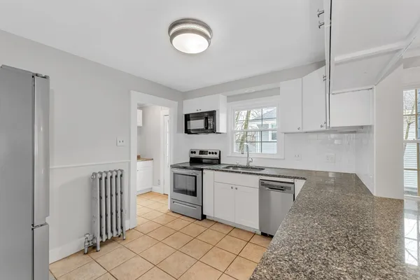 a kitchen with granite countertop a sink a stove top oven and cabinetry