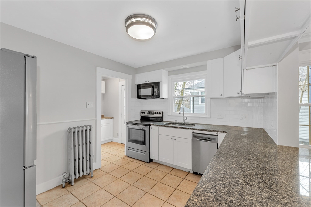21-23 Richards Road, Unit 21 Watertown, MA 02472 - Photo 3 of 28 a kitchen with granite countertop a sink a stove top oven and cabinetry