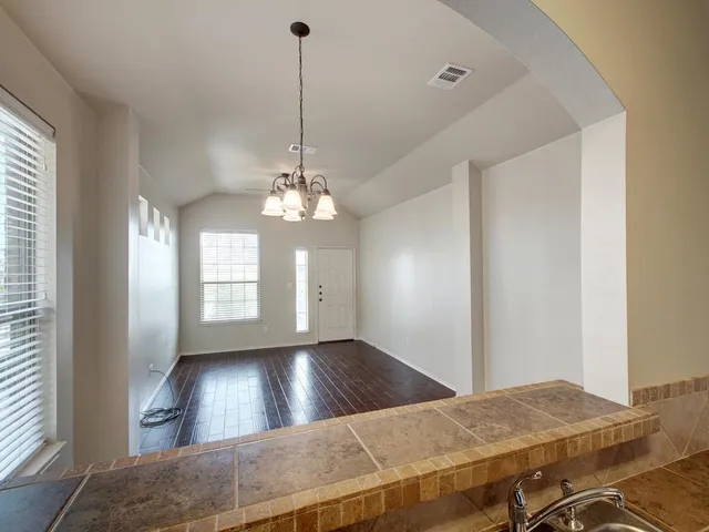 a view of a livingroom with a chandelier fan and windows