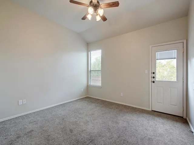 an empty room with a chandelier fan and windows