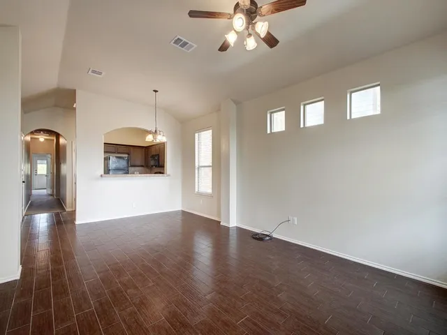 a view of an empty room with window and wooden floor